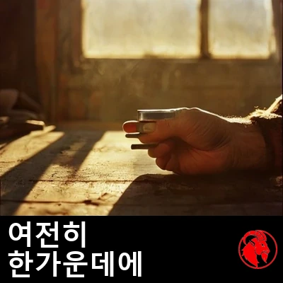 황금빛 조명 아래, 어수선한 작업대 위로 볼트 하나를 쥔 거친 손. 캡션: 그는 아직도 딱 일의 한가운데다