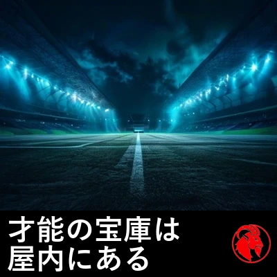 夜、照明に照らされた無人のスタジアム。ピッチの中央で一台のスマホだけが光る。キャプション：才能の育成場はいまや屋内。