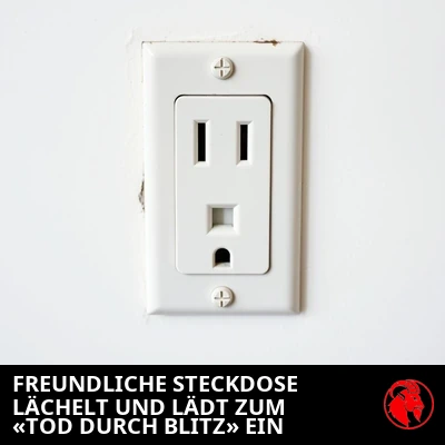Eine einfache US-Steckdose mit einer Buchse, deren Schlitze und Erdungsloch wie ein freundliches lächelndes Gesicht aussehen. Bildunterschrift: Freundliche Steckdose lächelt, lädt zum „Blitztod